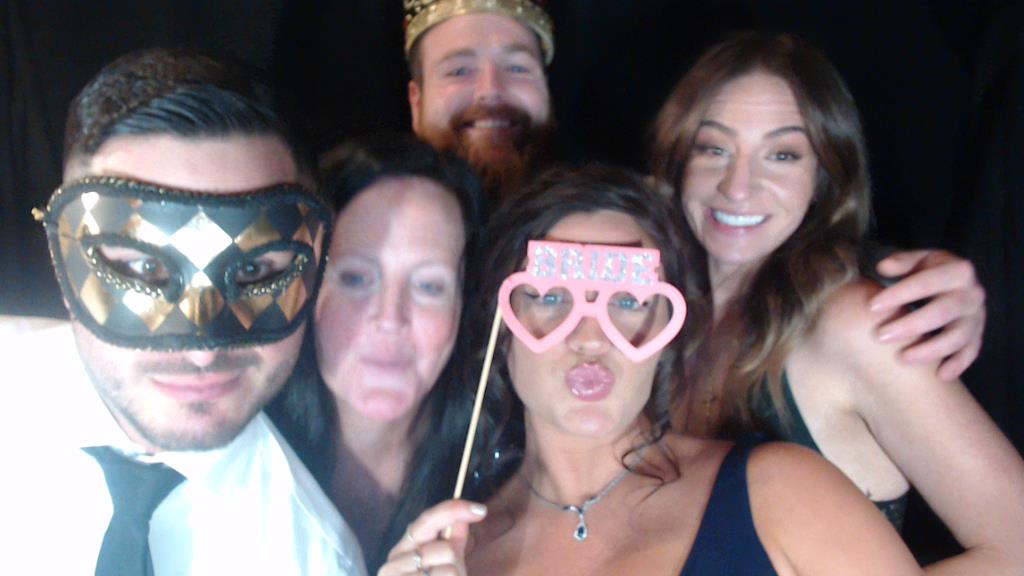 5 people in a photo booth at a wedding with props