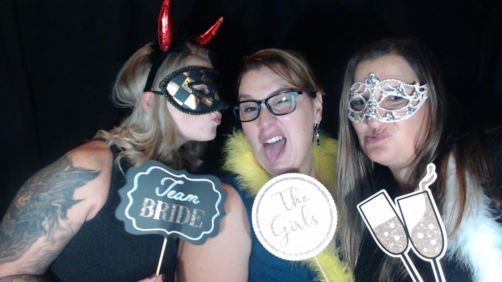 Girls in a photo booth at a wedding with props
