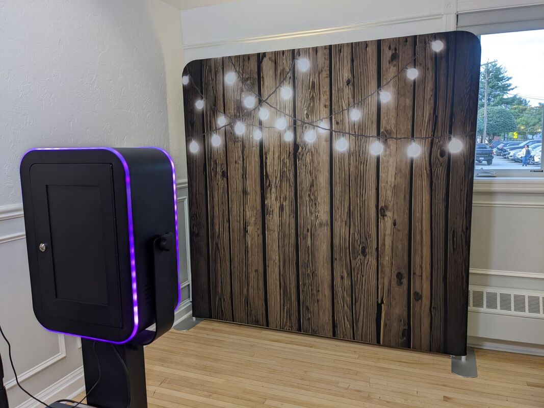 stand alone photo booth with dark wood and lights backdrop
